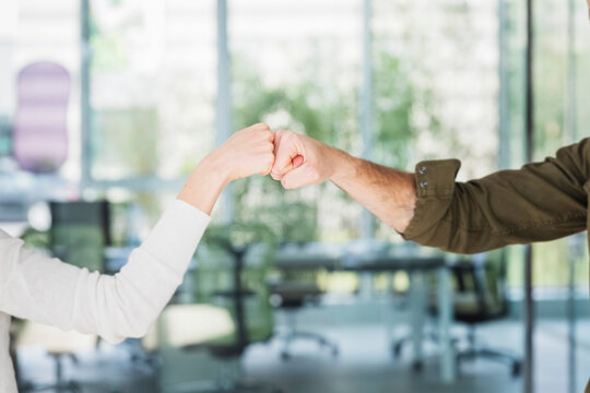 Male and female colleagues greeting with fist bumps in office