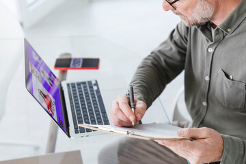 Mature businessman working during video conference through laptop at office