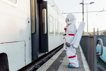 Young female astronaut standing at entrance of train at station