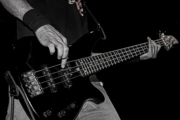 Obraz na płótnie Canvas Background Bass. Closeup hand playing bass. young musician playing bass, music background rock music concert, Black and white