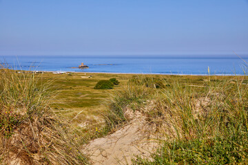 Image of St Ouens Bay from the sand dunes with Rocco Tower and blue sky. Selective Focus
