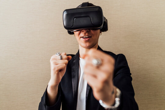 Businesswoman with virtual reality headset gesturing while standing in front of wall