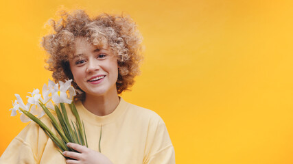 Attractive girl holding a bunch of white spring Flower in her hands. Girl with curly hair smiling...