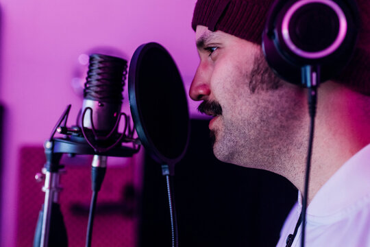 Male singer looking away while singing at studio