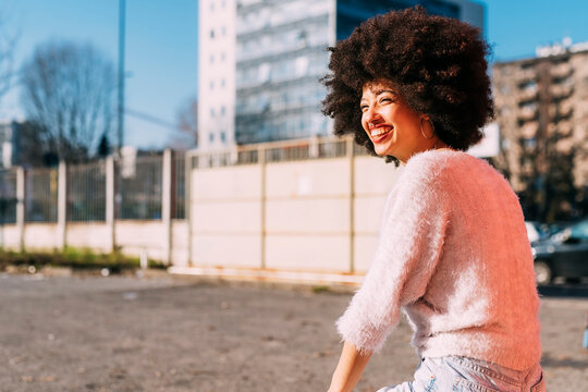 Cheerful afro hair woman looking away during sunny day