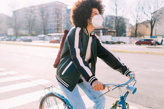 Woman with face mask cycling bicycle during sunny day