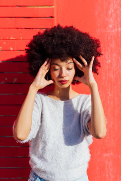 Young woman standing with head in hands on sunny day
