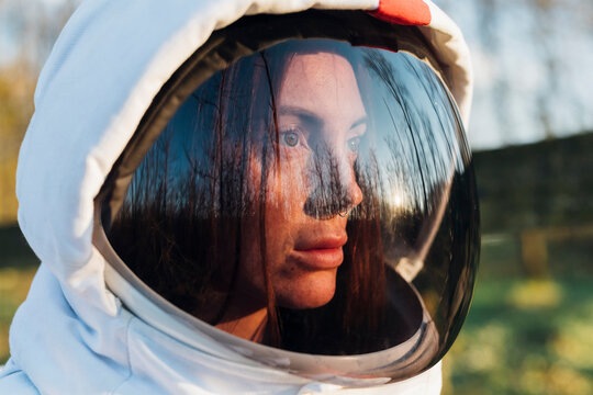 Female explorer wearing space helmet looking away in forest