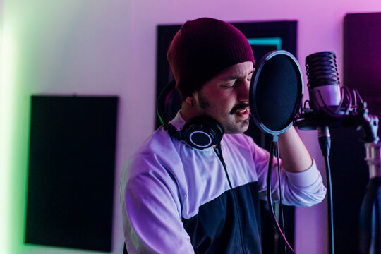 Man wearing knit hat singing at home studio