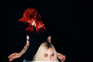 Female stylist tossing hair behind model at studio