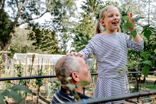 Grandfather with cheerful granddaughter in garden
