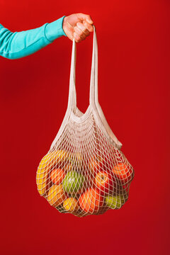 Arm Of Man Holding Reusable Cotton Mesh Bag With Fresh Fruits