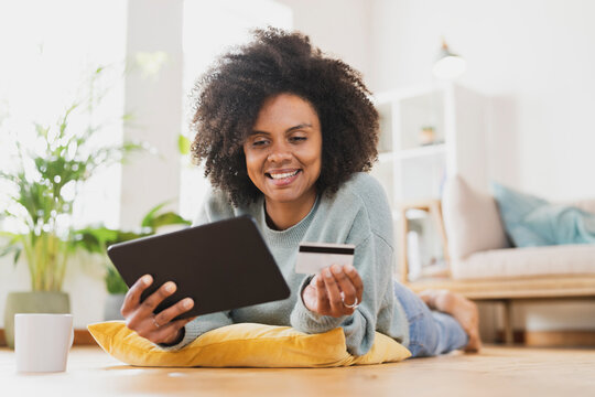 Young smiling woman with digital tablet and credit card at home