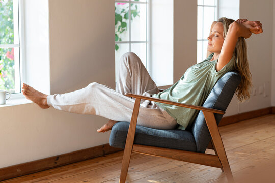 Woman with eyes closed resting on armchair at home