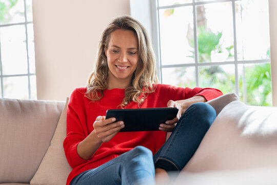 Smiling woman using digital tablet on couch