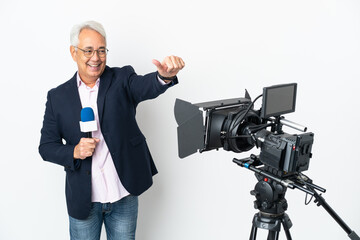 Reporter Middle age Brazilian man holding a microphone and reporting news isolated on white background giving a thumbs up gesture