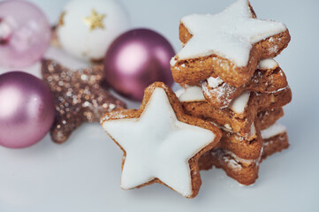 a stack of cinnamon stars on white background beside christmas tree balls, horizontal color photo