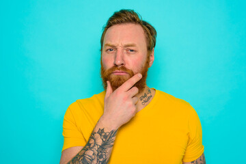 Man with yellow t-shirt and beard is very undecided