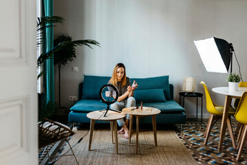 Female influencer filming tutorial through mobile phone at home