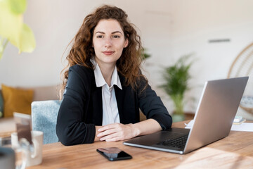 Beautiful female professional day dreaming while sitting in front of laptop at home office