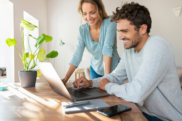 Cheerful couple working on laptop at home office