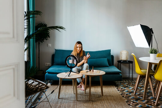 Female influencer filming tutorial through mobile phone at home - Powered by Adobe