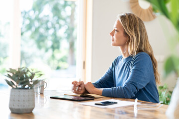 Blond businesswoman writing in diary while sitting at table