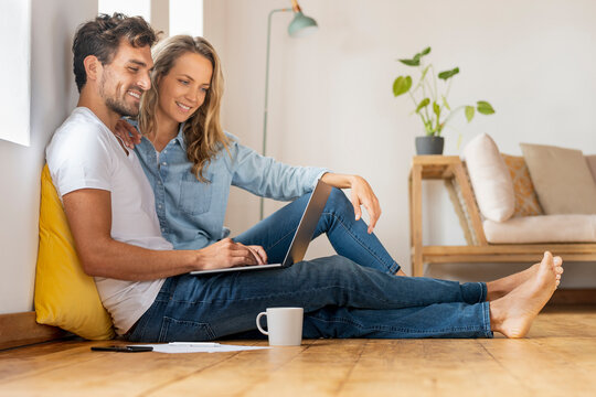 Relaxed couple looking at laptop while sitting together at home office