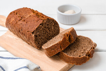 Freshly baked rye bread sliced on wooden board. Light wooden background with copy space.