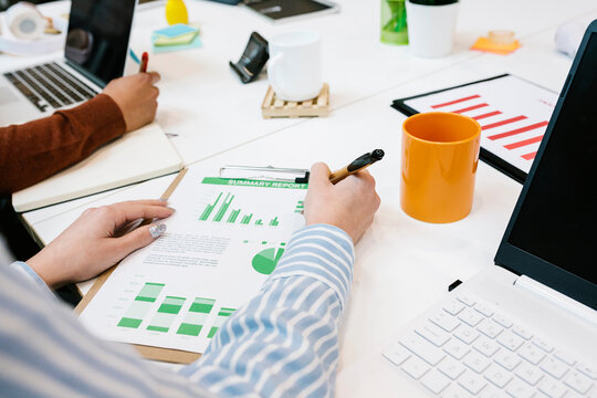 Businesswoman working on business plan by male colleague at desk in coworking office