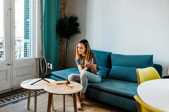Female influencer using ring light while filming make-up tutorial