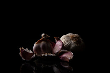Ajos morados sobre fondo negro. Ajo abierto con los dientes morados.