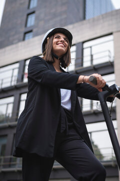 Smiling businesswoman looking away while standing with electric push scooter