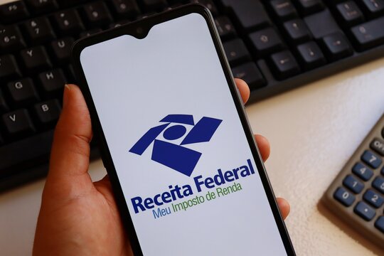 Receita Federal logo on smartphone screen. IRPF. Receita Federal (RFB) is the Brazilian federal revenue service agency. 