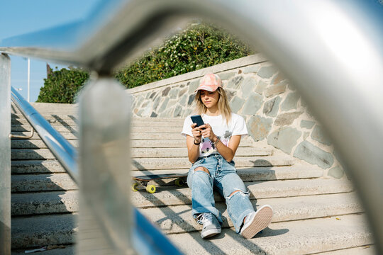 Mid adult woman wearing cap sitting on steps
