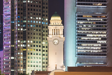Singapore, Clock tower of Victoria Theatre and Concert Hall at night with skyscrapers in background