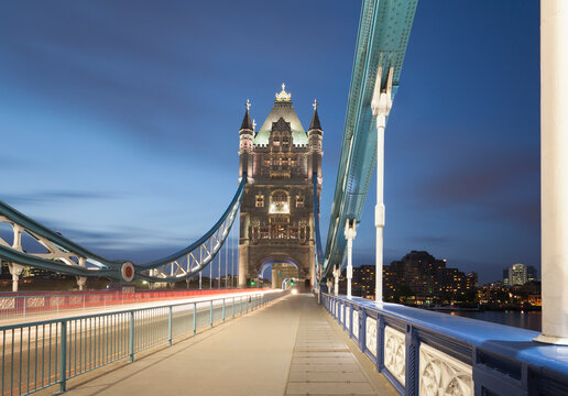 UK, England, London, Vehicle light trails across Tower Bridge at dusk