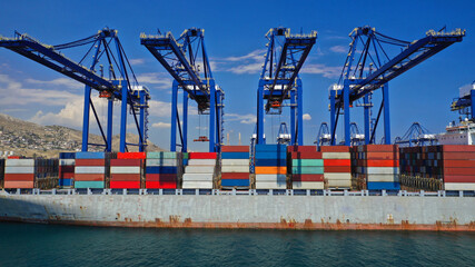 Fototapeta premium Aerial drone closeup photo of colourful container seaside port and logistics terminal of Perama in crane area while loading-unloading to container tanker vessel, Piraeus, Attica, Greece