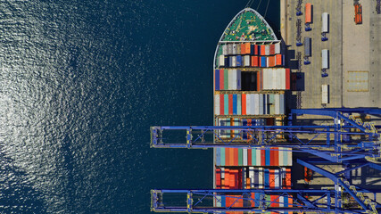 Aerial drone top down photo of industrial cargo container ship loading or unloading with help of...