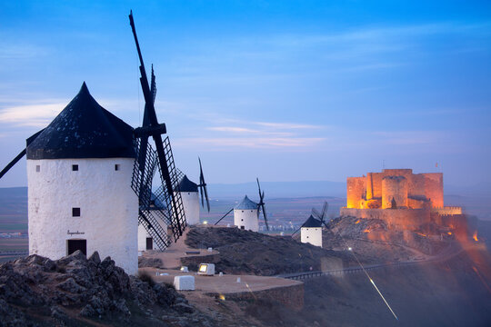 Spain, Province of Toledo, Consuegra, Historical windmills at dusk with&nbsp;Castle of La Muela&nbsp;in background