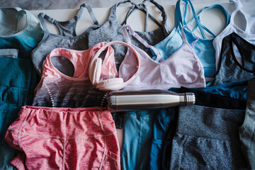 Woman sports clothes with water bottle and headphones at home