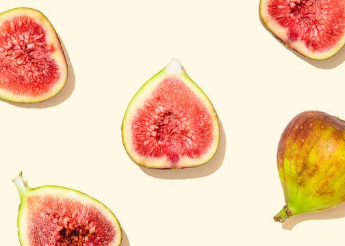 Studio shot of halved figs lying against light yellow background