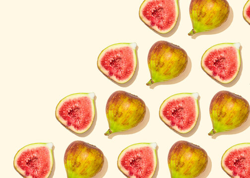 Pattern of halved figs flat laid against light yellow background