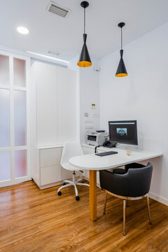Computer by printer and empty chairs at desk in dentist's clinic
