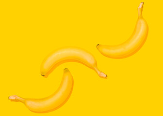 Studio shot of three bananas lying against yellow background