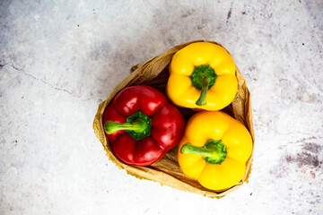 Studio shot of paper bag with single red and two yellow bell peppers