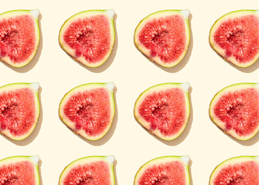 Pattern of halved figs flat laid against light yellow background