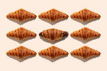Butter croissants and one chocolate croissant on beige background