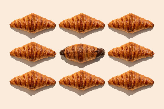 Butter croissants and one chocolate croissant on beige background