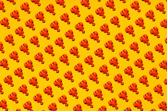 Pattern of rows of plastic lobsters flat laid against yellow background